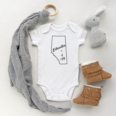 White baby bodysuit with graphic design of the province of Alberta outline and the saying Edmonton Heart of Alberta. Designed and printed by Bare It Designs.