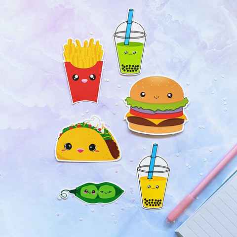 Decorative embellishment vinyl stickers of a variety of foods and drinks with cute faces. From the top, going clockwise is Bubble Tea (Avocado), Hamburger, Bubble Tea (Mango), Edamame, Taco, Fries. Stickers are drawn in the kawaii art style and printed by Bare It Designs, Edmonton, Canada.