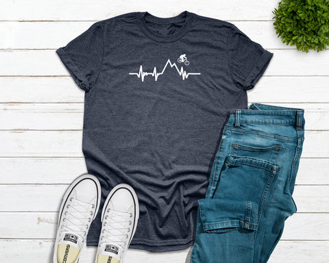 The t-shirt graphic of a heartbeat seamlessly intertwined with the mountain range as a daring mountain biker showcases the perfect harmony between the rush of adrenaline and the tranquility of the mountains. Designed and printed by Bare It Designs from Edmonton, Alberta.