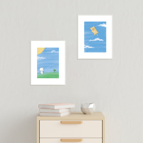 Flying A Cat First and Second Half (set of two) art prints by Bare It Designs, Edmonton, AB, Canada. A white cat is shown holding a kite string that is attached to an orange cat on another art print and the cat is flying in the air like a kite on a beautiful summer sunny day with blue skies.