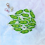 Cute kawaii peas in a pod fridge magnet designed by Bare It Designs from Edmonton, AB, Canada. Multiple peas in a pod magnets in a pile with one peas in a pod magnet highlighted in the center.