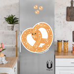 Product picture of a cute flexible pretzel twist fridge magnet with a background example of pretzel twist magnets clinging to a stainless steel fridge. Pretzel twist magnet is designed by Bare It Designs.