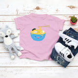Light pink toddler t-shirt with a cute happy ramen noodle bowl drawing in the kawaii art style. Designed and printed by Bare It Designs.