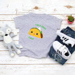 Grey toddler t-shirt with a cute classic hard shelled taco with the saying "Taco Bout Cute" drawing in the kawaii art style. Designed and printed by Bare It Designs.